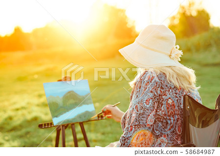 an elderly woman paints a picture in nature an elderly woman paints a picture in nature 58684987