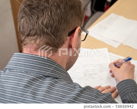 A man writing up paperwork at work. A man writing up paperwork at work. 58688942