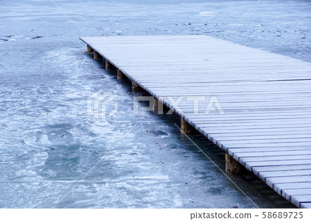 pier on the lake. Wooden bridge in forest in winter time with blue frozen lake. Lake for fishing 58689725