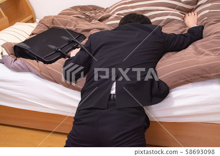 Office worker falling into bed Office worker falling into bed 58693098