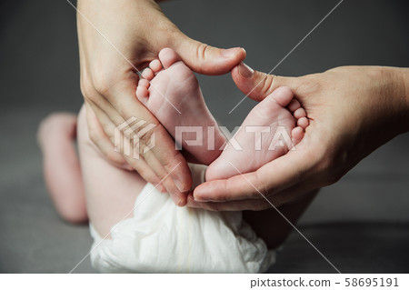 Mother holding newborn baby feet in hands 58695191