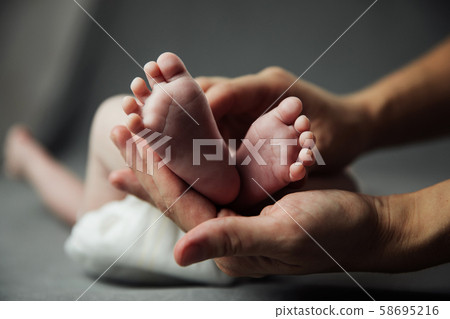 Mother holding newborn baby feet in hands 58695216