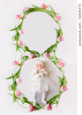 Little beautiful newborn girl lying on the bed among the flowers. 58696775