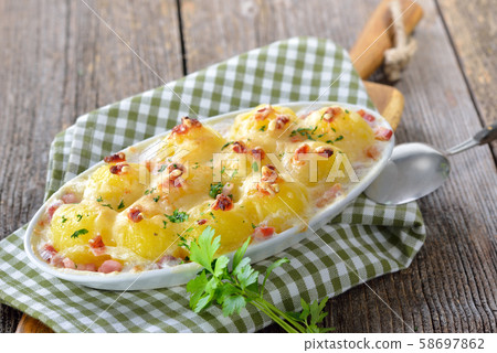 Hearty potato dumplings baked with cheese and bacon, freshly served from the oven Hearty potato dumplings baked with cheese and bacon, freshly served from the oven 58697862