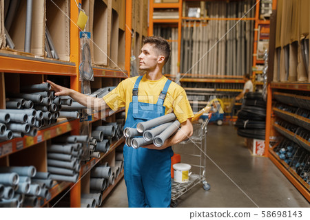 Male builder choosing piping in hardware store Male builder choosing piping in hardware store 58698143