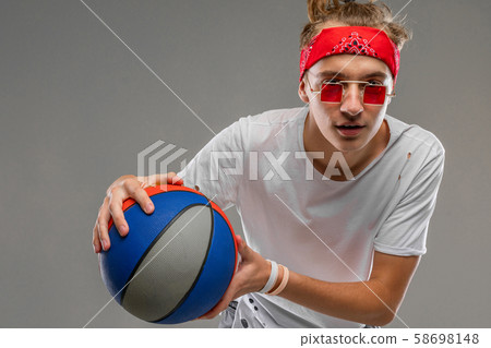 cool young man on a gray background with a ball in his hands, half shot of a teenager in a light T 58698148
