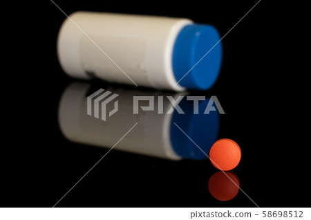 Orange pharmacy tablet isolated on black glass 58698512