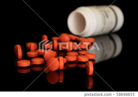 Orange pharmacy tablet isolated on black glass 58698655