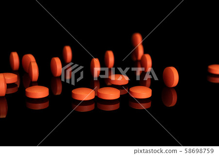 Orange pharmacy tablet isolated on black glass Orange pharmacy tablet isolated on black glass 58698759