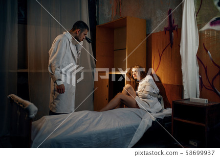 Psychiatrist with torch, patient in strait jacket 58699937
