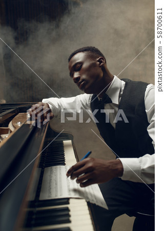 Black grand piano musician poses on the stage 58700611