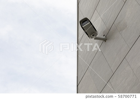 Safety cctv camera on gray tiled building facade, sky on other half of photo, diagonal view. Safety cctv camera on gray tiled building facade, sky on other half of photo, diagonal view. 58700771