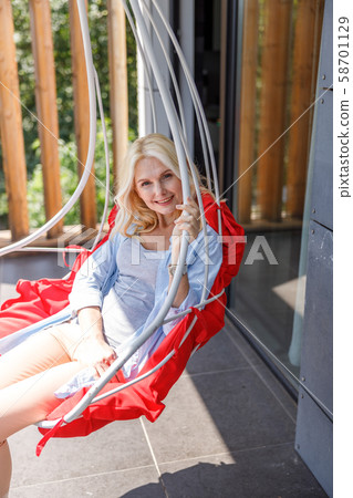 Smiling pretty lady is sitting on balcony Smiling pretty lady is sitting on balcony 58701129