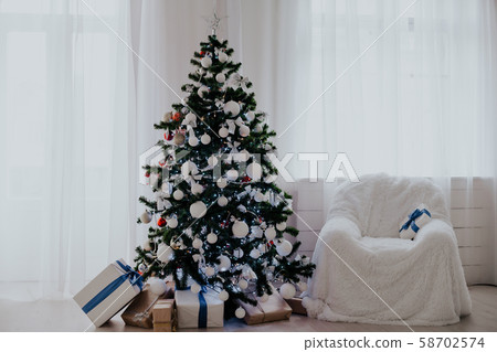Christmas tree stands in a white room Christmas decoration gifts 58702574