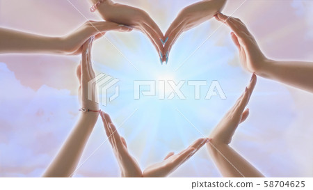 A group of youth makes a heart shape out of their hands. 58704625