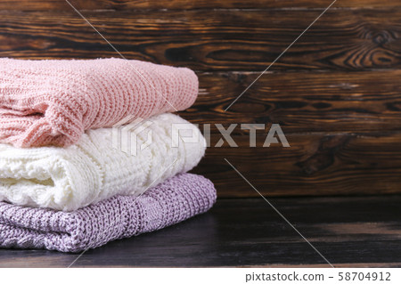 Pile of knitted sweaters of different colors and 58704912