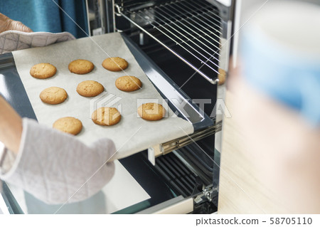 Woman is taking baking tray with baking Woman is taking baking tray with baking 58705110