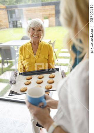 Smiling mature lady doing baking in the kitchen Smiling mature lady doing baking in the kitchen 58705116