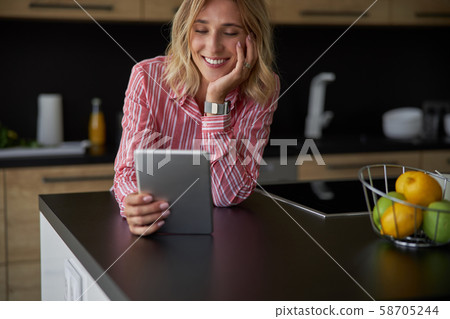 Happy young lady is using tablet at home Happy young lady is using tablet at home 58705244