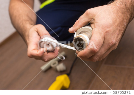 Preparing to connect the water supply. Winding the tape. Hands plumbing close-up. 58705271