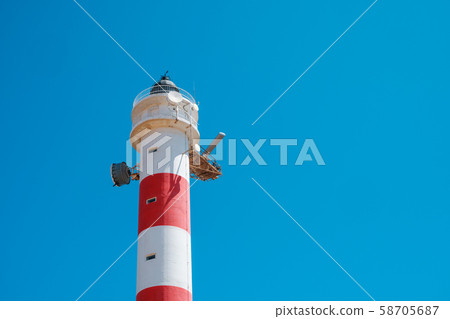 red,white lighthouse tower isolated on blue sky  - 58705687