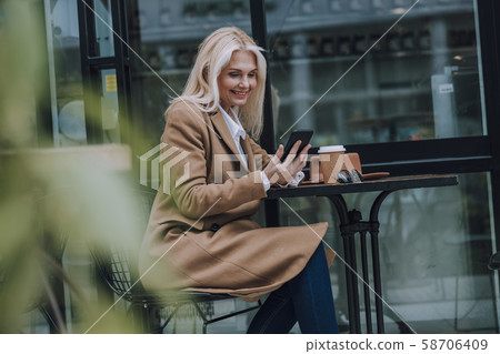 Happy woman is looking on smartphone screen Happy woman is looking on smartphone screen 58706409