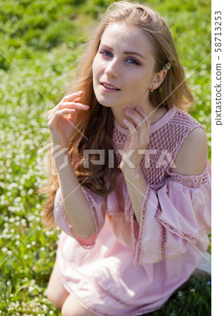 Beautiful blonde woman in dress collects flowers in the garden 58713253