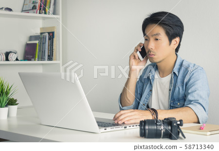 Asian Photographer or Freelancer Use Smartphone and Laptop in Home Office in Vintage Tone 58713340