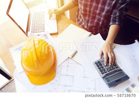 Asian engineer , architect woman using calculator for accounting and analyzing building structure from blueprint and paper chart in front of computer laptop at office work space. Asian engineer , architect woman using calculator for accounting and analyzing building structure from blueprint and paper chart in front of computer laptop at office work space. 58718670