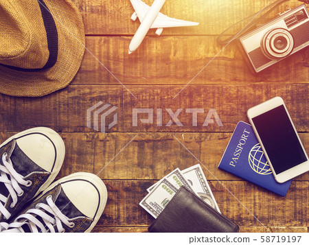 flat lay of passport ,mobile, plane model , sneakers , wallet , camera and traveler's accessories items on wooden background with copy space. travel and vacation concept 58719197