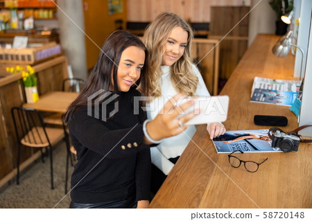 Two Smiling Young Friends Taking Selfie With Smartphone In Cafe 58720148
