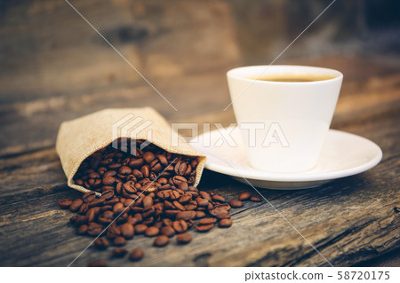 Cup and coffee beans fall out of the bag on an old Cup and coffee beans fall out of the bag on an old 58720175