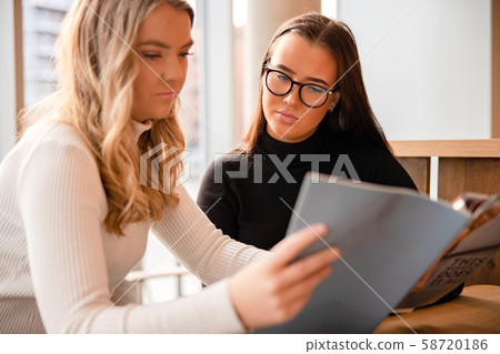Close-up of Serious Young Somen Discussing Over Publication In Cafe Close-up of Serious Young Somen Discussing Over Publication In Cafe 58720186