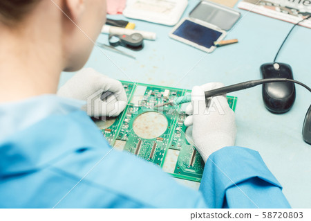 Technician soldering components to a PCB 58720803