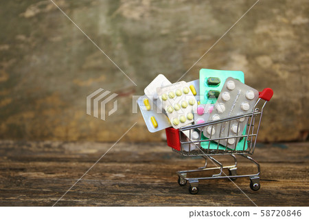Shopping cart with pills on old wood background. Shopping cart with pills on old wood background. 58720846