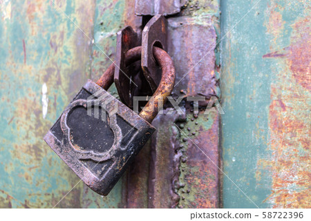 Old and rusty padlock with scratches locks the steel doors of an abandoned vault 58722396