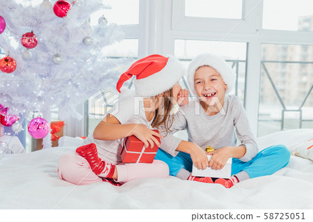 Little girl whispering funny story in brother's ear, covering her mouth. Both of them are laughing. Little girl whispering funny story in brother's ear, covering her mouth. Both of them are laughing. 58725051