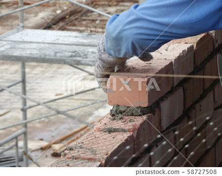 Bricklayer lay clay brick and stacked it together using cement mortar to form walls at the construction site. Necessary tools required for this job.  58727508