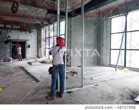 Drywall installation work in progress by construction workers at the construction site. It is the easiest and cheapest way to do partition for interior wall. Drywall installation work in progress by construction workers at the construction site. It is the easiest and cheapest way to do partition for interior wall. 58727998