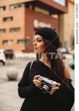 woman holding retro camera and taking picture 58728669