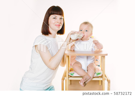 A young beautiful mother feeds a baby from a bottle A young beautiful mother feeds a baby from a bottle 58732172