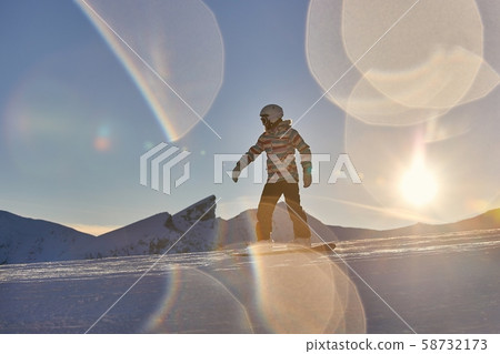 Snowboarder in sun flare, water drops on lens Snowboarder in sun flare, water drops on lens 58732173