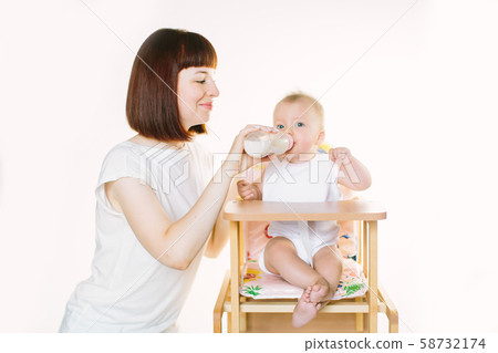 A young beautiful mother feeds a baby from a bottle A young beautiful mother feeds a baby from a bottle 58732174