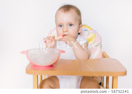 portrait of happy young baby girl sitting on high chair and feed her self portrait of happy young baby girl sitting on high chair and feed her self 58732241