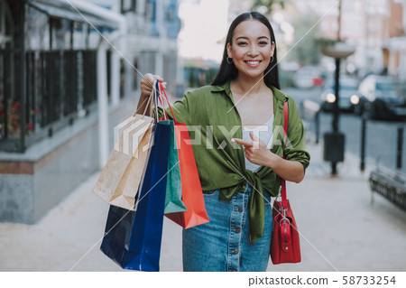 Happy pretty lady holding up bags outsdoors Happy pretty lady holding up bags outsdoors 58733254