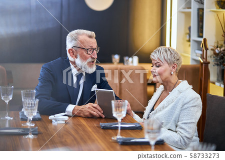 Portrait of cheerful senior couple on date, with laptop in hands chat and enjoy 58733273