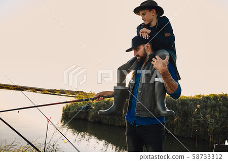 The first joint fishing of adult father and teen son in warm, sunny day. The first joint fishing of adult father and teen son in warm, sunny day. 58733312