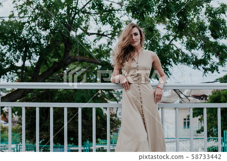 Portrait of a beautiful fashionable woman in a beige dress on a walk 58733442