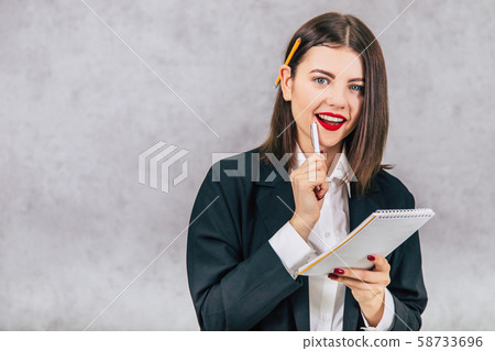 Cute business women standing with pencil behind her ear and listening, writing down something into Cute business women standing with pencil behind her ear and listening, writing down something into 58733696