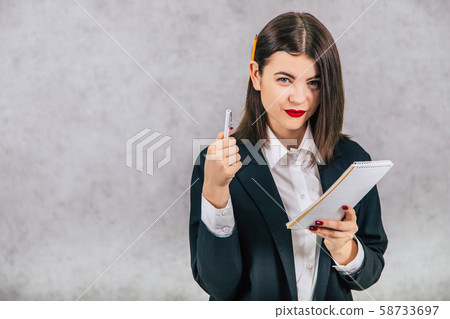 Cute business women standing with pencil behind her ear and listening, writing down something into Cute business women standing with pencil behind her ear and listening, writing down something into 58733697